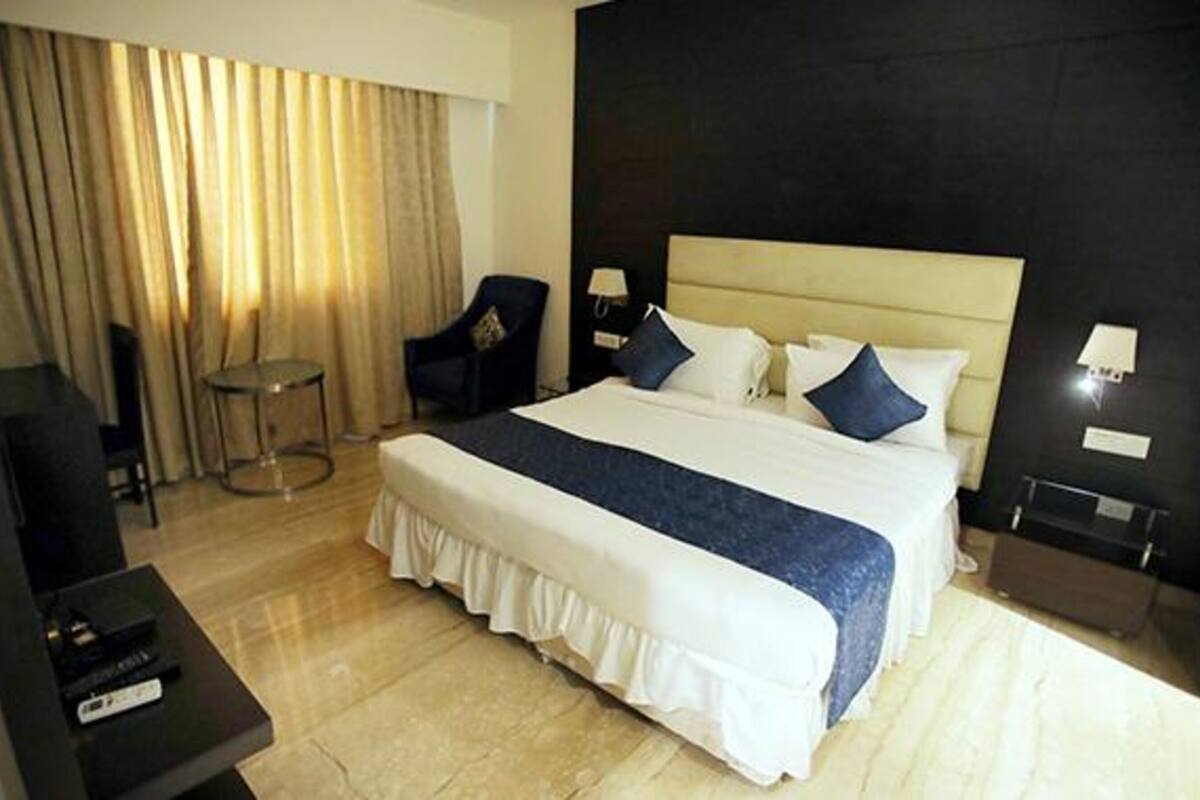 A hotel room with a large bed, a desk, a chair, and a small table.