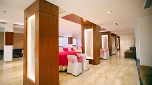 A modern hotel lobby with wooden pillars, a reception desk, and a seating area with chairs and a table. - FabHotel Prime Bellmont (Noida)