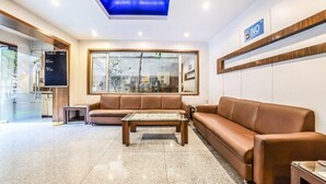 A modern lobby with a brown leather sofa, a coffee table, and a large window with a view of the city. - FabHotel Prime Rapid Lakme Executive (Pune)