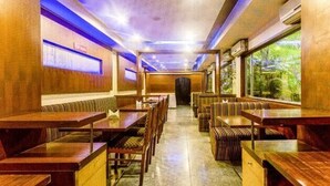 A train dining car with wooden tables and benches, large windows, and a tiled floor. - FabHotel Prime Rapid Lakme Executive (Pune)