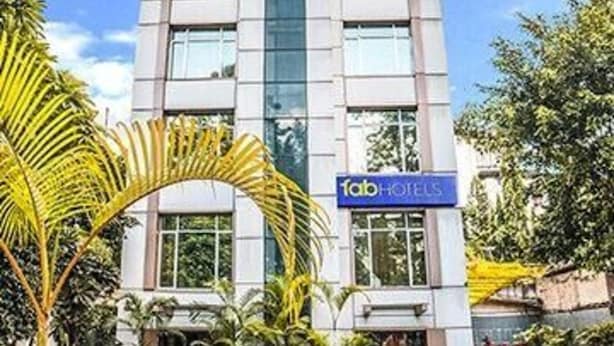 A modern hotel building with a central glass tower, a sign reading "Tab Hotels," and a well-maintained garden with potted plants. - FabHotel Prime Rapid Lakme Executive (Pune)