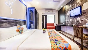 A hotel room with a bed, a TV, a desk, and a patterned rug. - FabHotel Prime Rapid Lakme Executive (Pune)