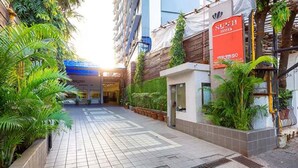 A hotel entrance with a tiled pathway, potted plants, and a sign for 'Sukyo Hotel'. - FabHotel Prime Sukh (Mumbai)