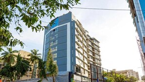 A multi-story building with a modern design, featuring a mix of glass and concrete facades. - FabHotel Prime Sukh (Mumbai)