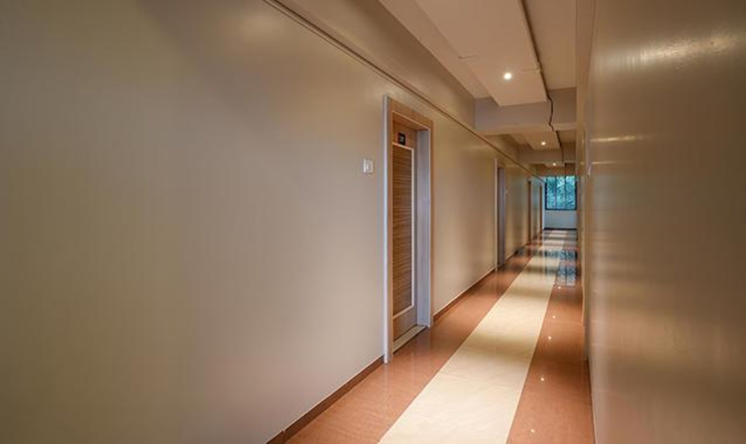 Un long couloir étroit, doté d’un plancher en bois et de murs aux couleurs claires.