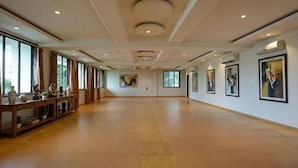 A spacious room with wooden flooring, large windows, and artwork on the walls. - FabHotel Prime Rester Select Chakan (Rajgurunagar)