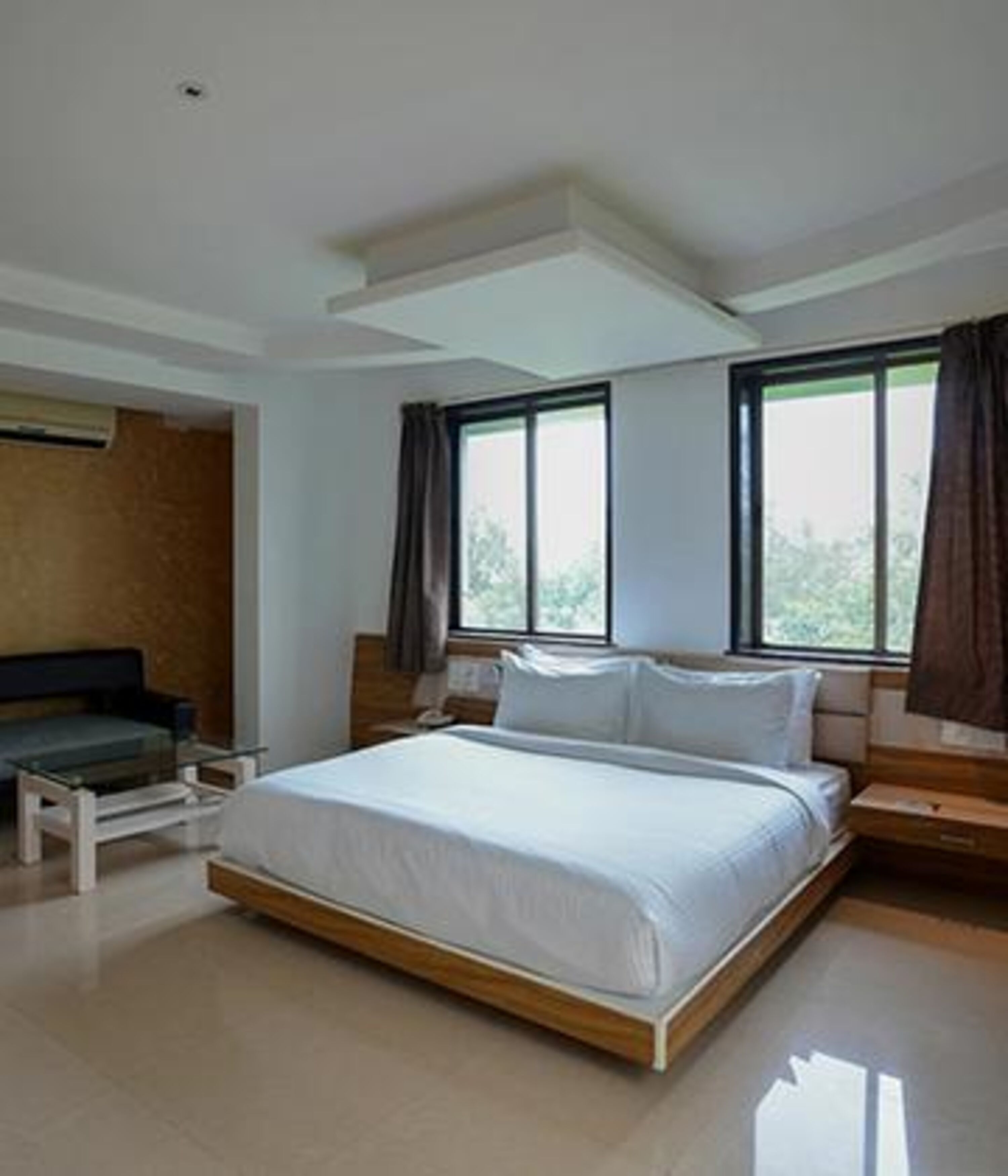 Un dormitorio moderno con una cama grande, una mesita de noche y un ventanal con cortinas.