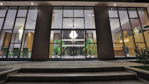 A hotel entrance with large glass doors, a chandelier, and potted plants. - FabHotel Prime Empyrean (Gandhinagar)