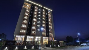 A multi-story hotel with illuminated windows and a well-lit entrance. - FabHotel Prime Empyrean (Gandhinagar)