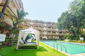 A hotel with a pool, a tented area with lounge chairs, and a sign indicating no food or beverage allowed. - FabHotel Emerald Highland (Candolim)