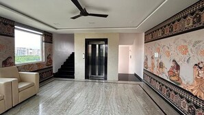 Amplia habitación con piso de mármol, un sofá, un ventilador de techo y una escalera que da a un ascensor.
