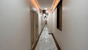 Un pasillo con suelo de mármol, puertas de madera e iluminación empotrada.