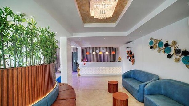 A modern lobby with a reception desk, blue sofas, wooden accents, and decorative wall art. - FabHotel Prime Liverpool Blue (Bengaluru)