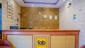 A reception desk with a wooden panel wall, a clock, and a sign for Fab Hotels. - FabExpress New Deepak (Mumbai)