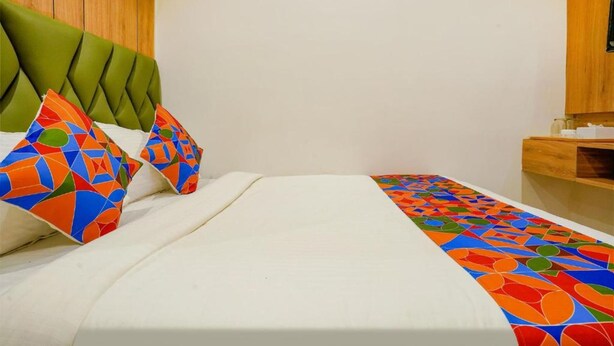 Cama bem arrumada com colchão branco e almofadas geométricas coloridas.