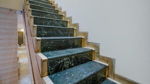 A staircase with marble steps and wooden handrails. - FabExpress New Deepak (Mumbai)