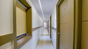 A long, narrow hotel corridor with doors on both sides, numbered 306 and 307, and a tiled floor. - FabExpress New Deepak (Mumbai)