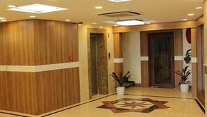 A hotel lobby with a wooden reception desk, a patterned floor, and potted plants. - FabHotel Prime Stalin Pleasant Park (Chennai)