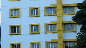 A multi-story building with a repeating pattern of windows and a central yellow structural element. - FabHotel Prime Stalin Pleasant Park (Chennai)