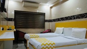A hotel room with two beds, a desk, and a window with a closed blind. - FabHotel Prime Stalin Pleasant Park (Chennai)