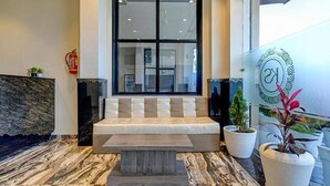 A reception area with a marble floor, a cushioned bench, and potted plants. - FabHotel Prime Kanha Shree (Indore)