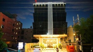 A modern hotel with a glass facade, a car parked in front, and a sign indicating it is a hotel. - FabHotel Prime Kanha Shree (Indore)