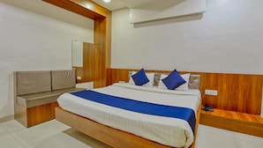 A bedroom with a large bed, a wooden headboard, a bedside table, and a built-in bench. - FabHotel Ten Eleven Grand (Indore)