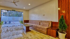 A reception area with a sofa, a small table, a potted plant, and a ceiling fan. - FabHotel Ten Eleven Grand (Indore)