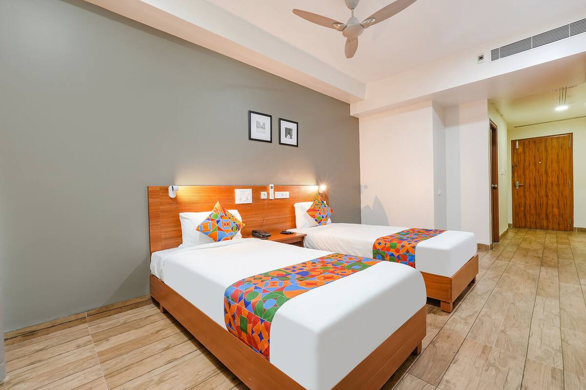 A hotel room with two beds, wooden headboards, and a ceiling fan.
