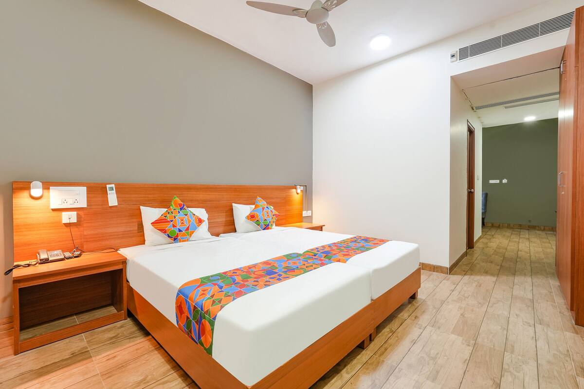 A hotel room with a large bed, wooden headboard, bedside tables, and a ceiling fan.