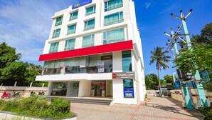 Um edifício de vários andares com uma saliência vermelha marcante, uma placa com 'Square OMN' e uma placa 'Fab Hotels'.