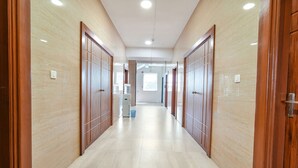 Um corredor com portas de madeira e chão de azulejos.