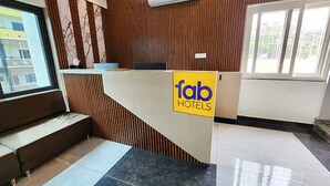 A reception desk with a 'fab hotels' sign, wooden paneling, and a view of the outside through a window. - FabHotel KSP Kings Inn (Bengaluru)