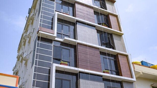 A multi-story building with a modern architectural design, featuring balconies with railings and windows. - FabHotel KSP Kings Inn (Bengaluru)
