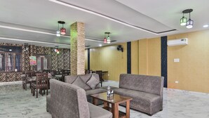 A hotel lobby with sofas, a coffee table, a fan, and a decorative pillar. - FabHotel Lucknow Inn (Lucknow)