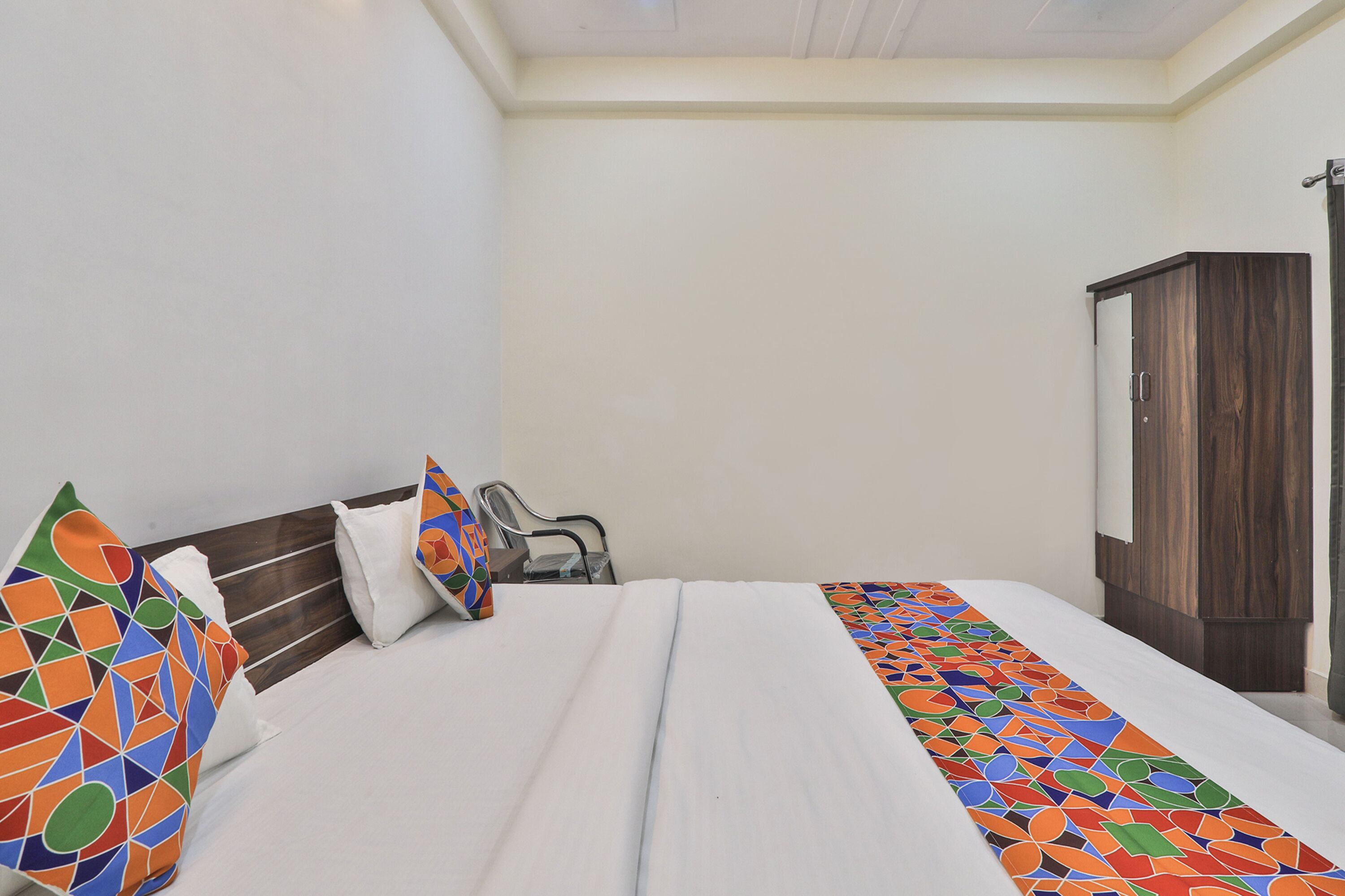 A neatly made bed with colorful pillows and a geometric-patterned bed runner.