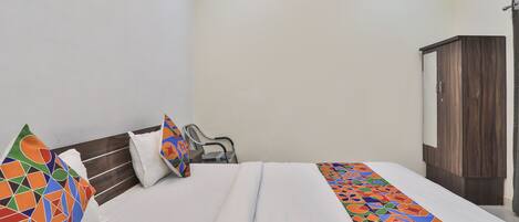 A neatly made bed with colorful pillows and a geometric-patterned bed runner.