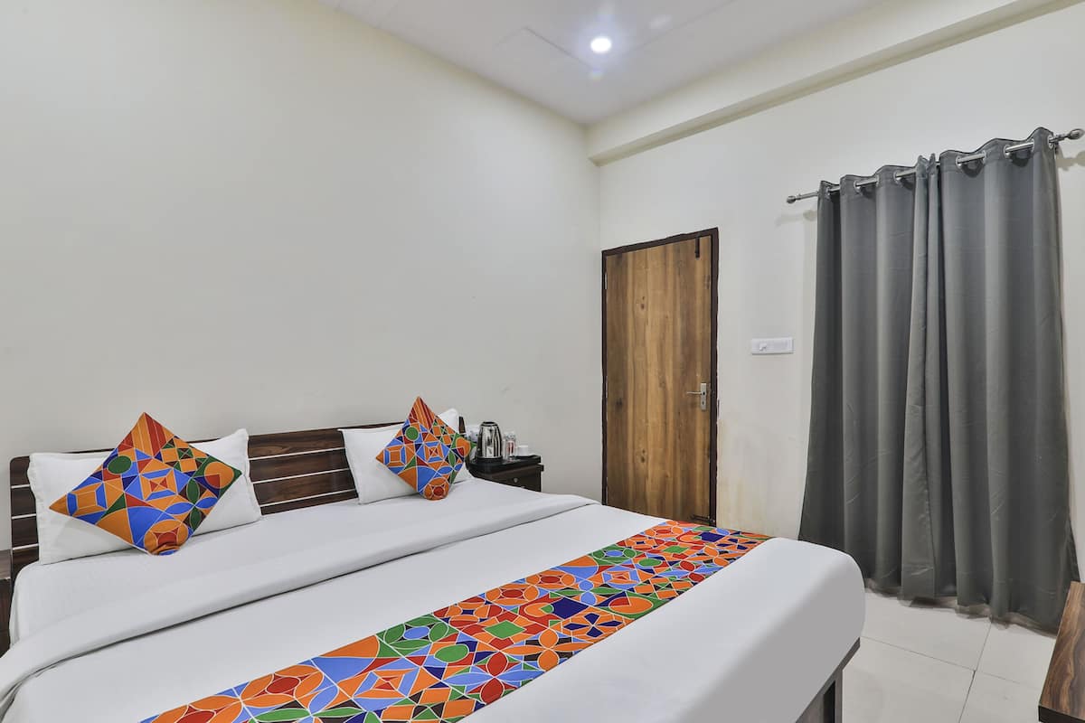 Una cama bien tendida con un corredor de cama de estampado geométrico colorido, un cabecero de madera y dos almohadas con diseño geométrico.