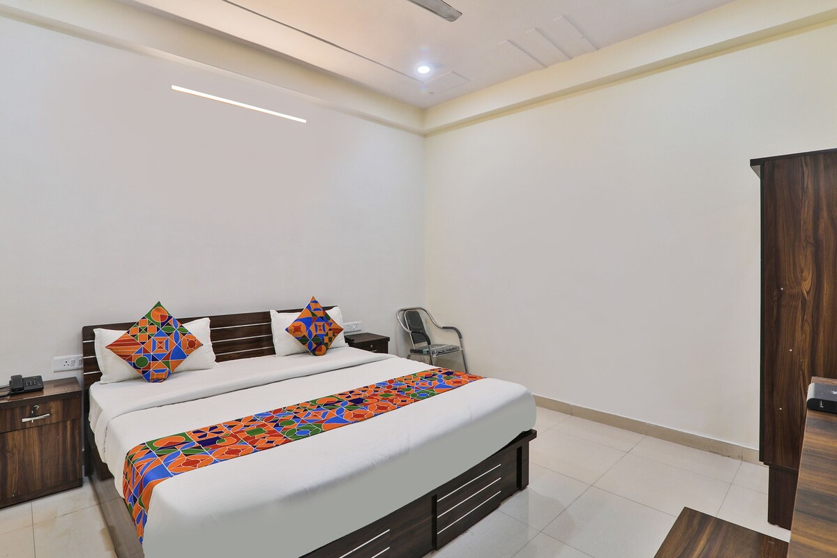 A neatly arranged hotel room with a large bed, a wooden wardrobe, and a chair.