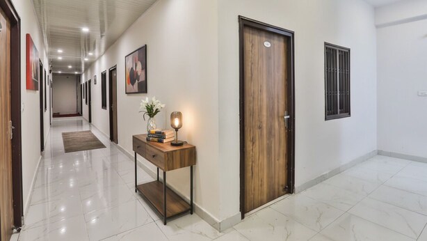 A hallway with a wooden door, a window, and a desk with a lamp and books. - FabHotel Lucknow Inn (Lucknow)