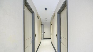 A narrow, well-lit hallway with doors on both sides, leading to a room at the end. - FabHotel Prime Y Stay (Greater Noida)