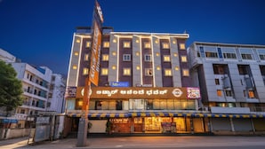 A multi-story hotel with a prominent signboard, multiple windows, and a storefront with a restaurant. - FabHotel Ginger Suites (Bengaluru)