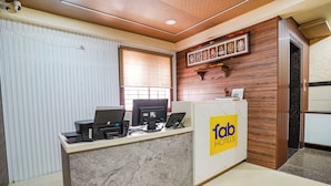 A hotel reception desk with a marble counter, a computer, and a phone. There are framed pictures on the wall above the counter. - FabHotel Ginger Suites (Bengaluru)
