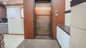 An elevator in a lobby with a marble floor, wooden paneling, and a reception desk. - FabHotel Ginger Suites (Bengaluru)