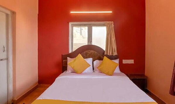 A room with a bed, a window with curtains, and a wall-mounted light. - FabHotel Green Castle Resort (Kodaikanal)