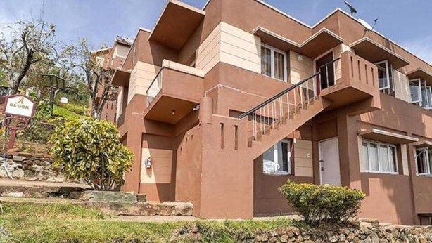 A multi-story building with a unique architectural design, featuring a prominent staircase and balconies. - FabHotel Green Castle Resort (Kodaikanal)