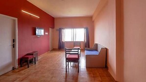 A room with a bed, a TV, a small table, and a window. - FabHotel Green Castle Resort (Kodaikanal)