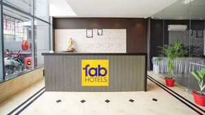 A hotel reception desk with a logo, a statue, and potted plants.