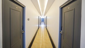 A long, narrow hallway with two doors on each side, leading to a bright end.