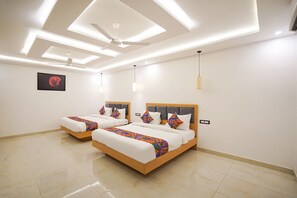 A modern bedroom with two beds, a ceiling fan, recessed lighting, and a framed artwork on the wall. - FabHotel Prime Kingston (Sohawal)